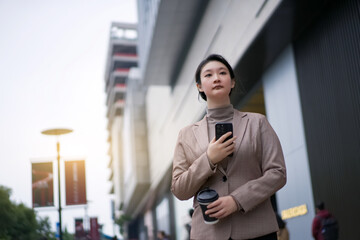 Confident Businesswoman Walking Outdoors with Mobile Phone