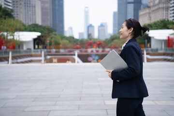Confident Businesswoman Walking With Laptop Outdoors