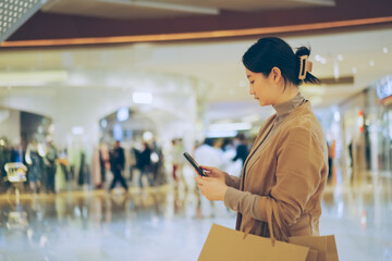 Woman with Shopping Bags Using Smartphone in Mall