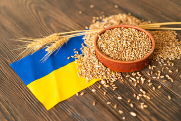Wheat grains with yellow and blue Ukrainian flag on wooden background. Export, sale, import of...