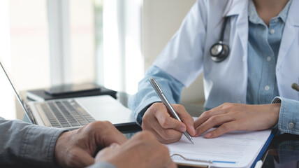Female doctor writing a prescription for her patient. Docotr filling medical insurance claim form at medical clinic, healthcare and medicine concept, close up