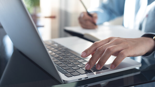 Business woman working on laptop computer and writing note on notebook. Female student searching the information on laptop computer during online studying, e-learning,  business planning