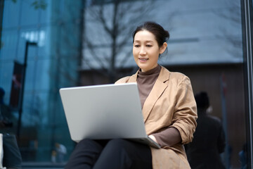 Young Professional Working on Laptop Outside Office