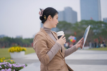 Businesswoman Checking Tablet with Coffee Outdoors