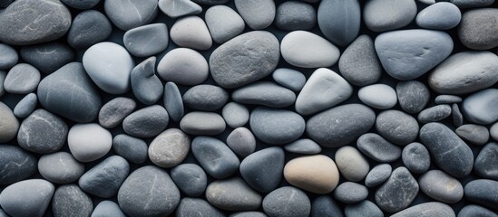 A closeup of a pattern of carmine cobblestones and rocks stacked on a beach, resembling a road surface. The mix of pebbles and gravel creates a unique flooring design