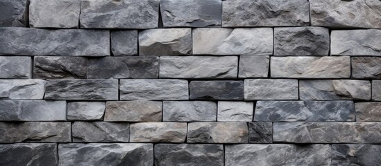 Obraz premium A closeup of a rectangular grey brick wall showcasing the intricate pattern of the brickwork. The composite material resembles a stone wall made of rock or cobblestone