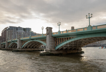 Fototapeta premium View of Southwark Bridge cross The River Thames in London. The side of a turquoise cast iron bridge, Curved steel Bridge, Space for text, Selective focus.