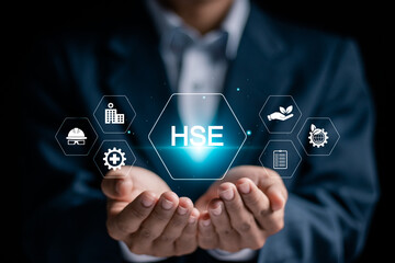 HSE, Health safety environment concept. Standard safe industrial work and industrial. Businessman holding HSE icon on virtual screen for business and organization. - obrazy, fototapety, plakaty