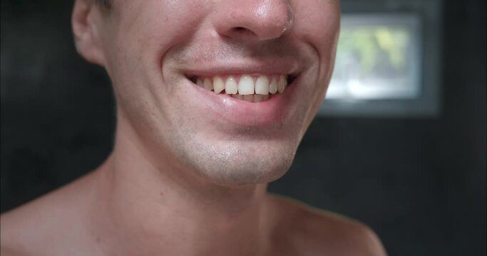 Close-up confident man in bathroom showing off his dazzling smile. Snow-white teeth and perfect smile eye-catching. Concept of success and attractiveness thanks to perfect teeth and charming smile.