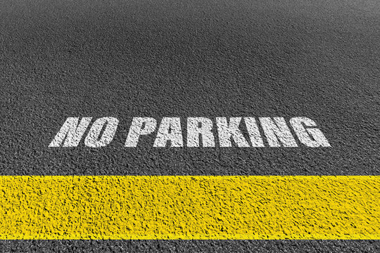 No parking signage on a concrete floor.No Parking Sign on the road. Yellow no parking lines on fresh road.