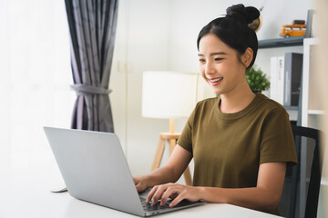 Young attractive female sitting at the desk and using laptop computer.