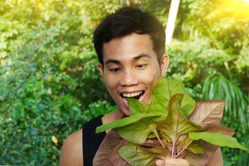 A happy young man is seen eating a salad from the garden directly after harvest