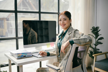 Obraz premium A woman is sitting at a desk with a computer monitor in front of her