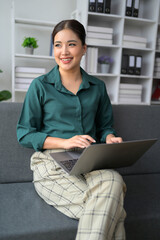 A woman is sitting on a couch with a laptop in front of her