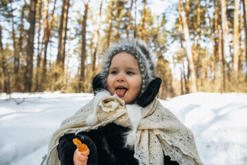 A little cute girl of European appearance in the style of the 90s. A child in a fur coat and shawl is walking in the fresh air.