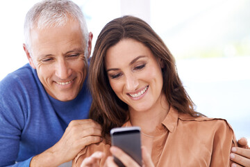 Couple, smartphone and smile in home to relax with reading, search and mobile app for contact with bonding. People, woman and mature man with phone for notification, typing or web connection in house