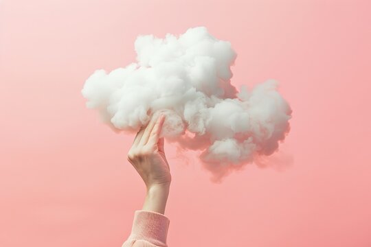 a womans hand is holding a cloud against pink background