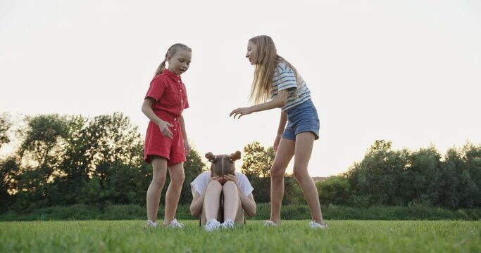 Upset Girl Crying as Peers Mock Her in Park - A Scene of Bullying Among Friends