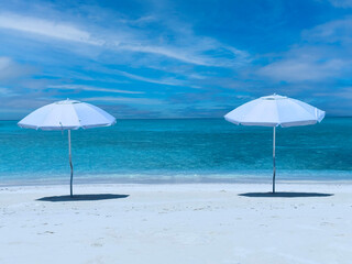 Summer tropical with white umbrella on the beach with  blue sky background