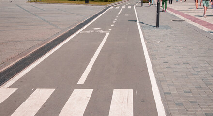A sign of a bicycle path and pedestrian crossing on the asphalt in a city park, close-up
