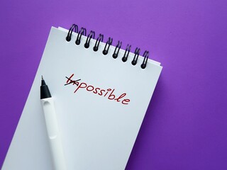 Notebook on purple background with text written IMPOSSIBLE crossed of to POSSIBLE,  keeping in mind...