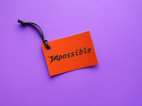Red tag on purple background with text written IMPOSSIBLE crossed of to POSSIBLE,  keeping in mind to make the impossible possible, focus on all the ways to accomplish your goals and make it happen