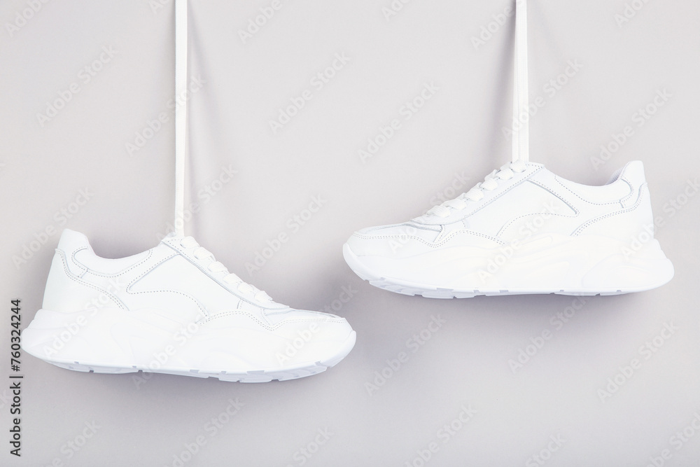 Wall mural pair of hanging white shoes on grey background