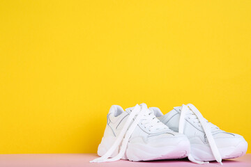 Pair of white shoes on yellow background