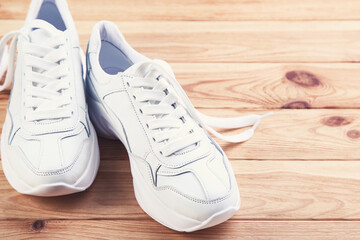 Pair of white shoes on brown wooden table - 760324282