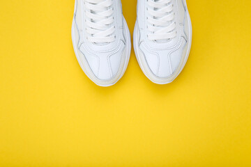 Pair of white shoes on yellow background
