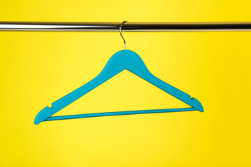 Wooden clothes hanger on yellow background