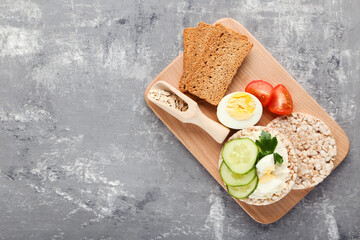 Crispbread with cream cheese, eggs and vegetables on grey background - 760325033