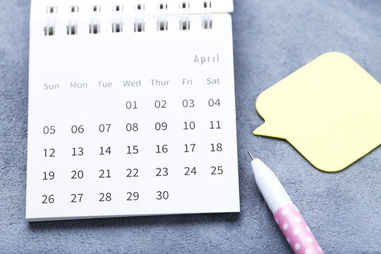 Calendar page with yellow speech bubble and pen on grey background