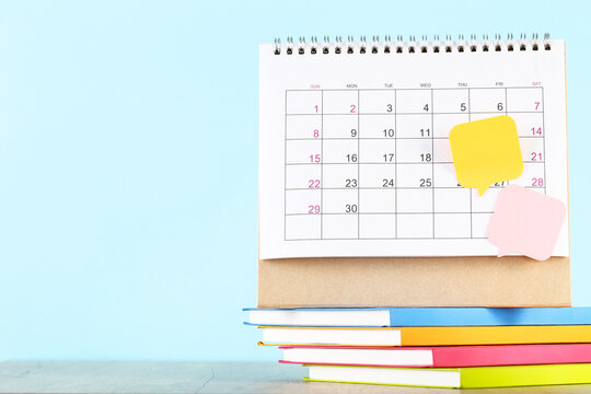 Calendar page with stack of notepads and speech bubbles on blue background