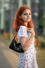 Portrait of a young beautiful red-haired girl outdoors.