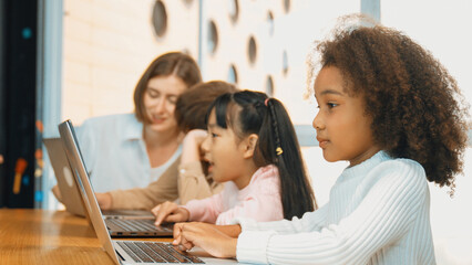 African girl play laptop with diverse friend learning prompt at STEM technology class....
