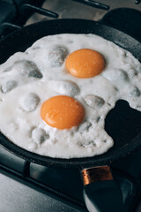 Frying egg in a cooking pan in the domestic kitchen.
