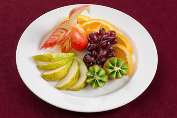 A plate of tropical fruits standing on red velvet
