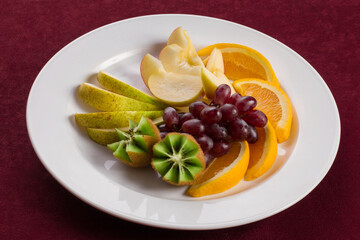 A plate of tropical fruits standing on red velvet