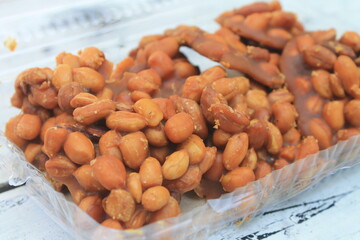 Indonesian snack called gulo kacang made from peanuts and brown sugar in mica plastic on the table