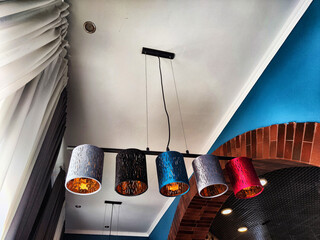 Modern Pendant Lights Hanging From a White Ceiling in a Contemporary Room. Five colorful pendant...