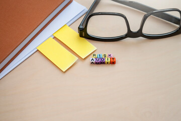 The word RISK AUDIT on the colorful cubes on the wooden office table. Business and risk audit concept