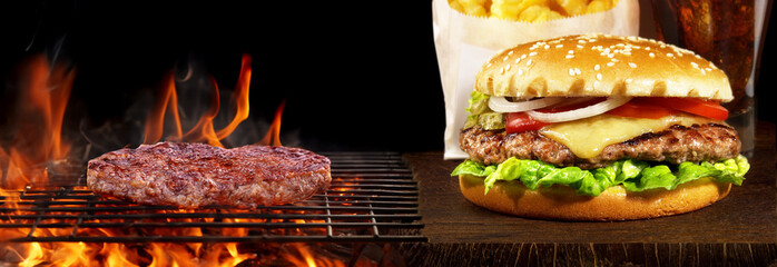 Grilled burger patty on a grill with flames with Hamburger on wooden Board - Panorama - 760379097