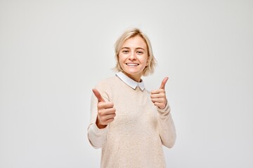 Cheerful young adult giving thumbs up against a white background, expressing positivity and...