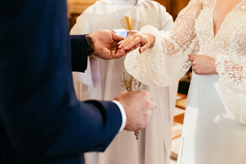 Exchange of wedding rings in a church couple holding hands during catholic ceremony