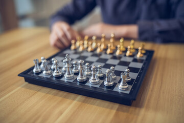 Strategic contemplation in action with a person making a chess move, focus on the golden and silver pieces. Business strategy success concept