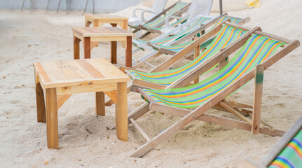 Empty beach chairs with wooden table on beach.