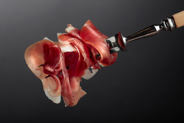 Slices of prosciutto on a fork.