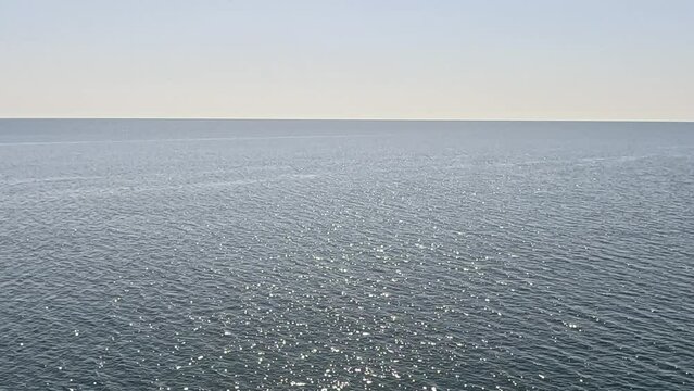 Sea water surface. Aerial view over clear azure sea water. Sun glare. Abstract nautical summer ocean nature. Holiday, vacation and travel concept. Nobody. Slow motion. Weather and climate change