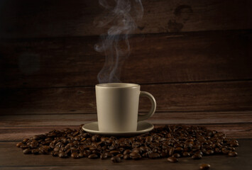 appetizing cup of steaming coffee with coffee beans all around on a wooden table
